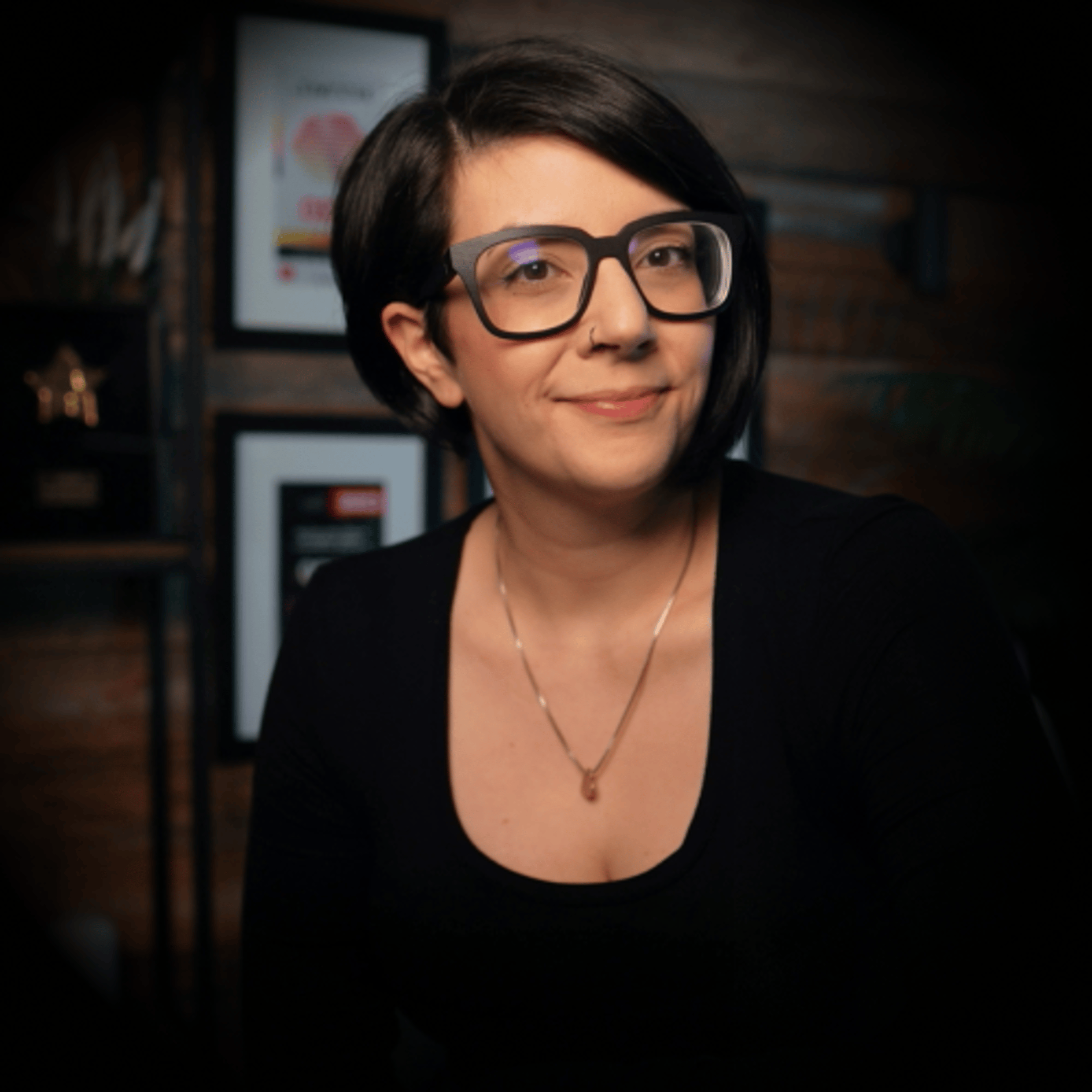 A photo of Salma at her desk with pink and yellow lights, plants and pictures hung up on the wall in the background